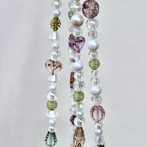 A close-up highlighting the heirloom-quality beads with heart and floral details on the Antique Garden hanger.