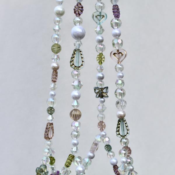 Detail shot of the eclectic mix of carved and metallic accent beads on this unique plant accessory.