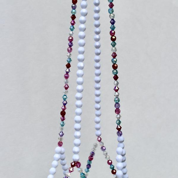 Macro detail of the raspberry, plum, and teal crystal beads contrasting with frosted white beads.