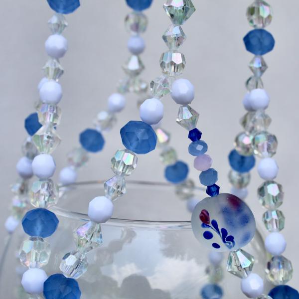 A close-up of the hand-painted floral glass beads and milky white accents on this porcelain-inspired plant hanger.