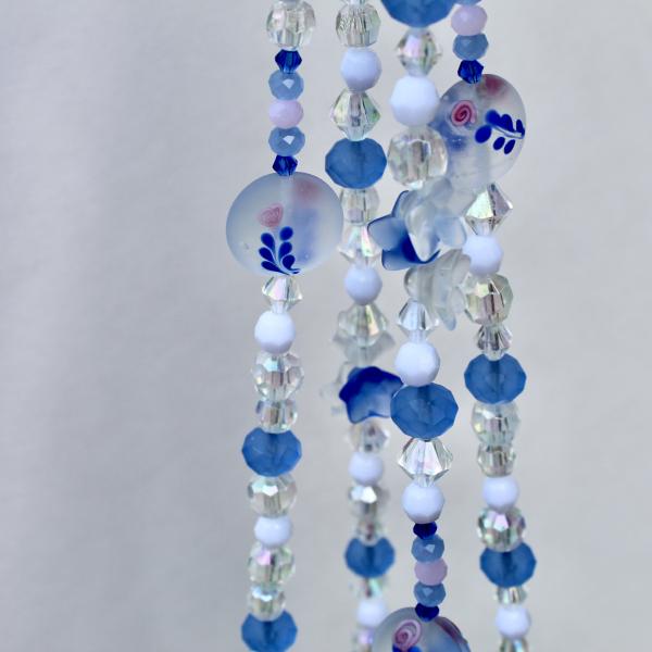 The Blue Delft Bloom hanger styled as an elegant, handcrafted character piece for a plant display.