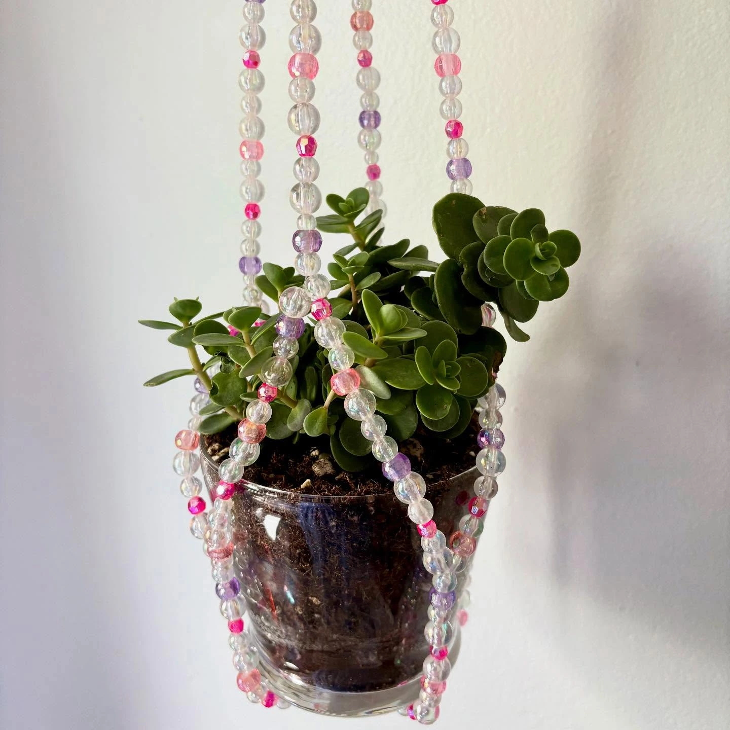 Founder of Bead & Bloom crafting a beaded plant hanger in a bright workshop.
