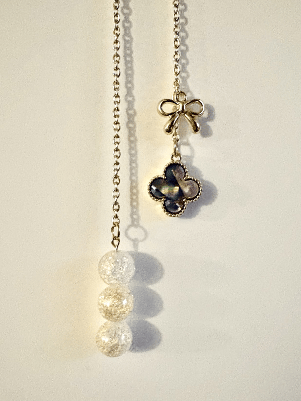 Close-up detail shot of the Moon Bow and Clover Charm.
