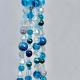 A close-up of the iridescent crystal, teal, and deep blue glass beads used in this coastal decor piece.