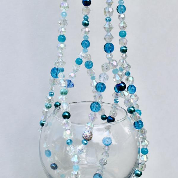 This handmade beachy plant hanger styled as a serene statement piece for a bathroom or sunroom.